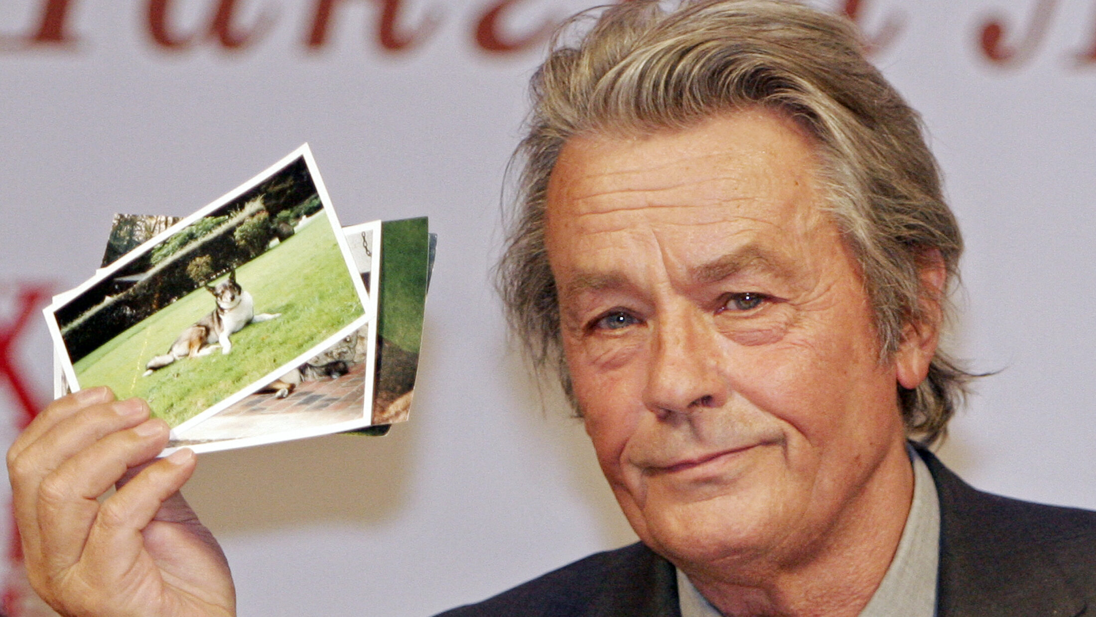 Der französische Schauspieler Alain Delon zeigt während seiner Pressekonferenz in Moskau am 16. März 2005 Bilder von zwei Hunden, die er von Alexander Lebed, einem russischen General und Politiker, der im April 2002 bei einem Hubschrauberunfall in Sibirien ums Leben kam, geschenkt bekommen hat