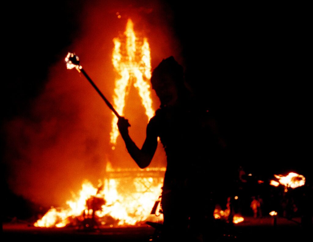 Ein Tänzer jongliert mit Feuer, während ein 52 Fuß großer Holzmann am 2. September 2000 während des 15. jährlichen Burning Man Festivals in der Black Rock Wüste bei Gerlach, Nevada, in Flammen aufgeht